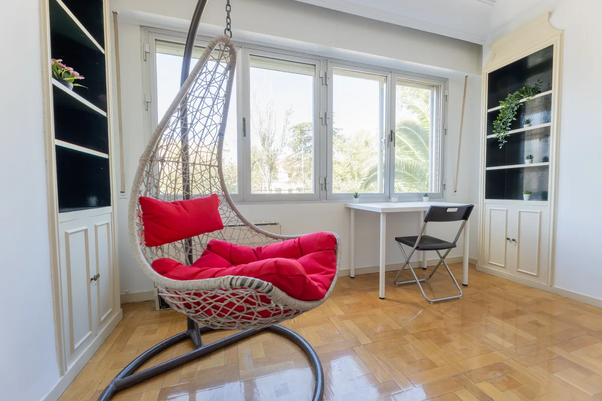 Habitación luminosa de una vivienda gestionada por Verantia, con silla colgante, escritorio y ventana